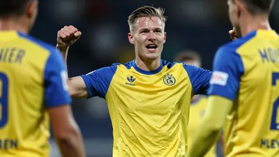 A tight action crop of an anonymous Molde player celebrating a goal with a teammate, wearing a yellow and blue kit with...